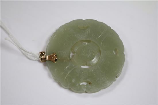 A gold mounted circular carved jade pendant, 2in.